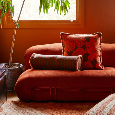 Living room with sofa and floral cushion, and Boucle Stripe Chocolate Pouffe