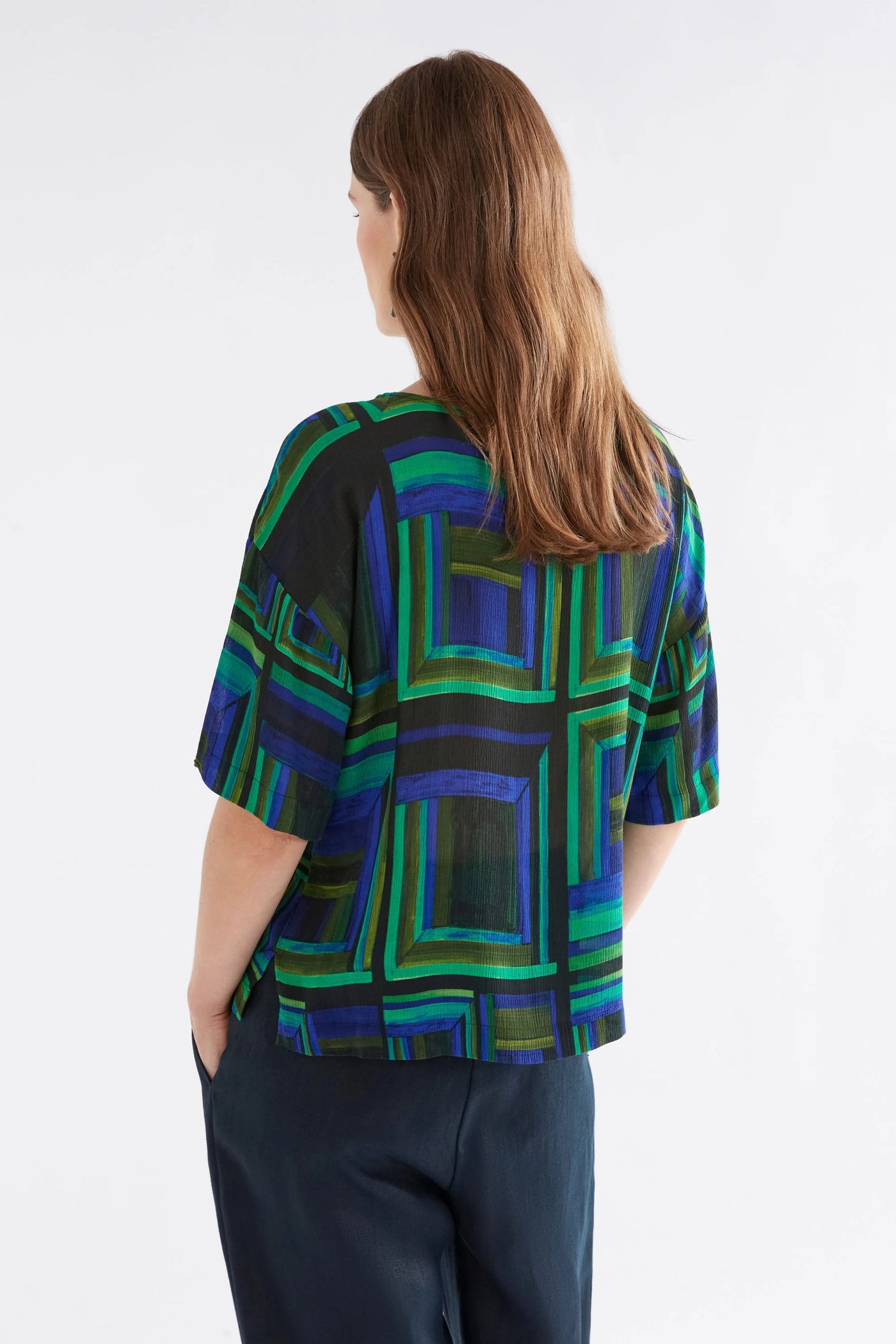 Woman facing the back wearing black pants and Soma top  in salome print