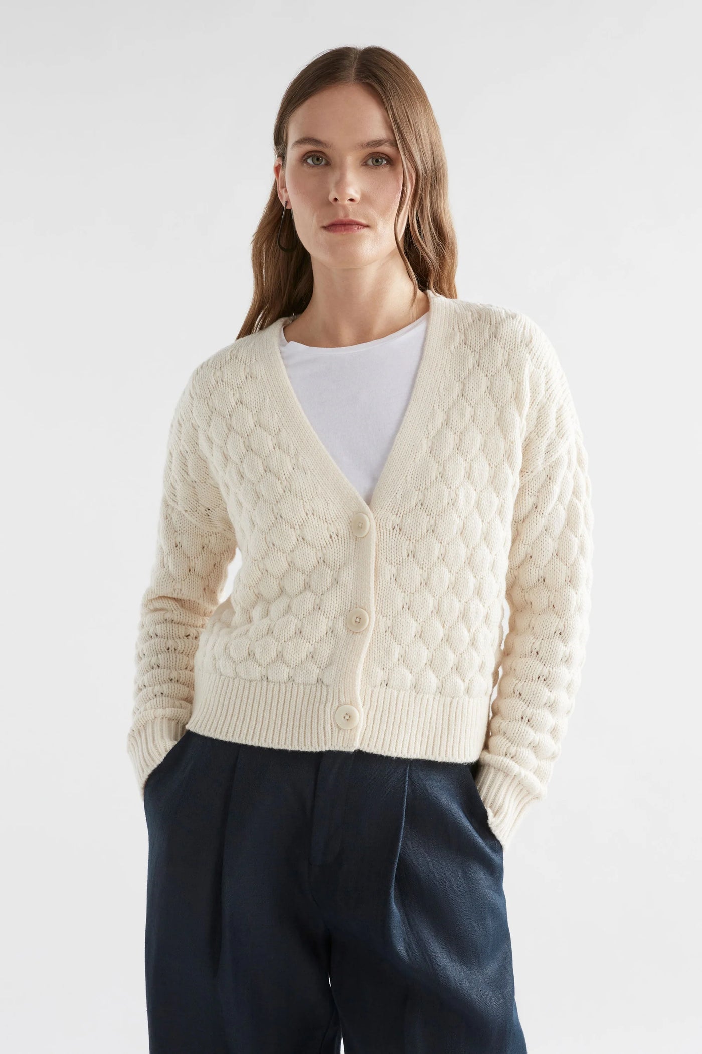 Woman wearing black pants, white top with emmer cardigan in oatmeal colour