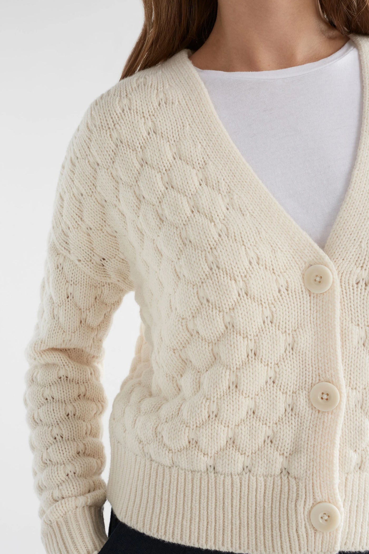 Woman wearing white top with emmer cardigan in oatmeal colour