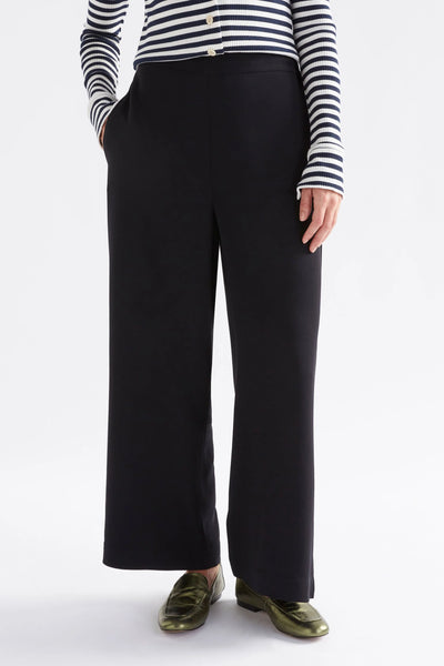 Woman wearing long sleeve stripe top and black pants and hand in the pocket of the pants