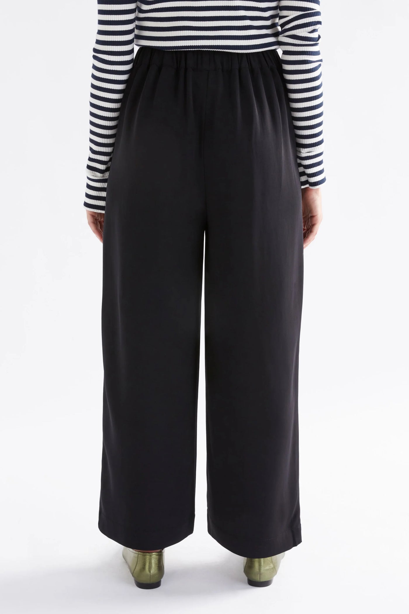 woman facing the back wearing long sleeve stripe top and black alden pants