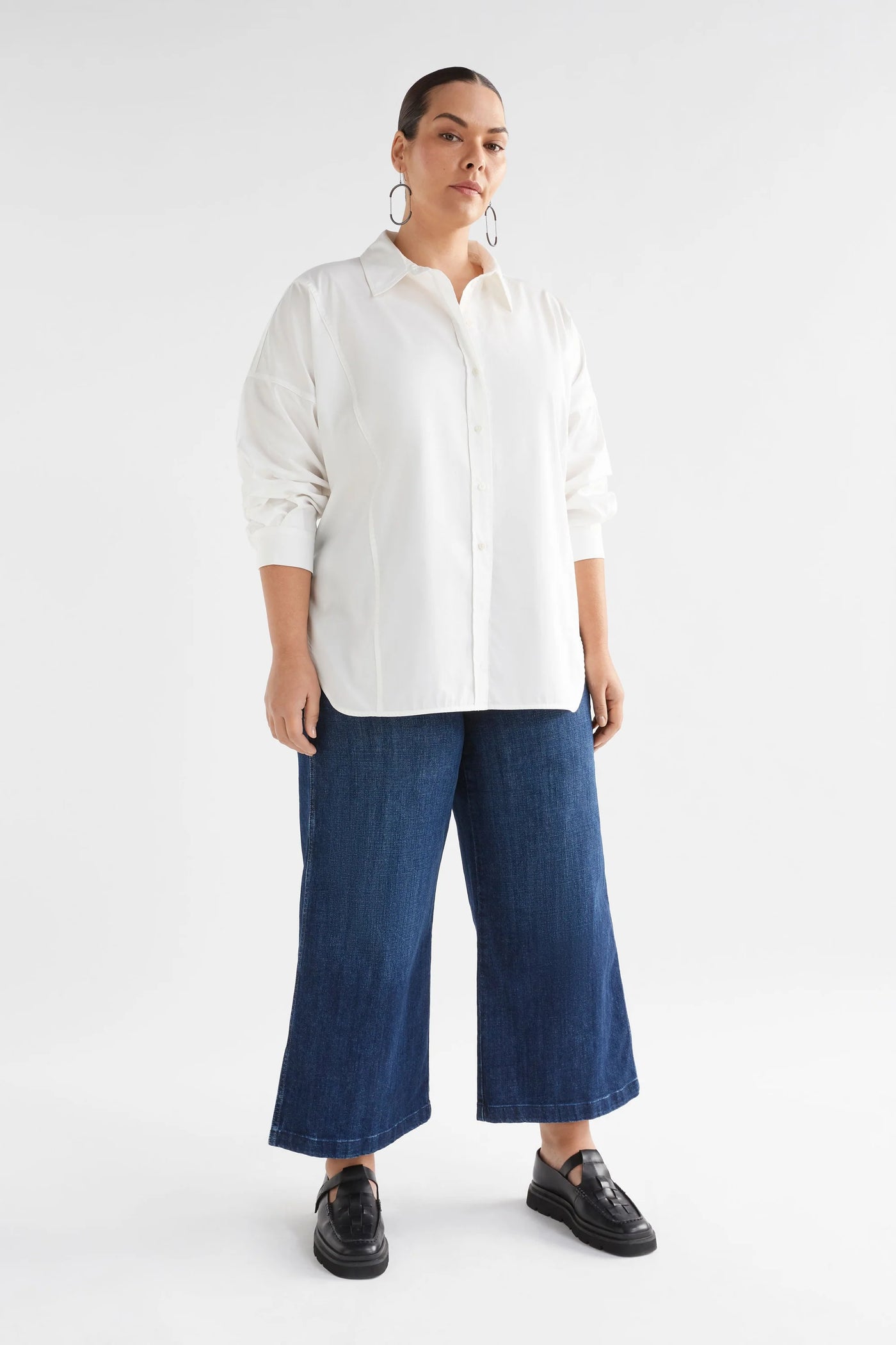 Plus size woman wearing tiga shirt in white and dark denim pants