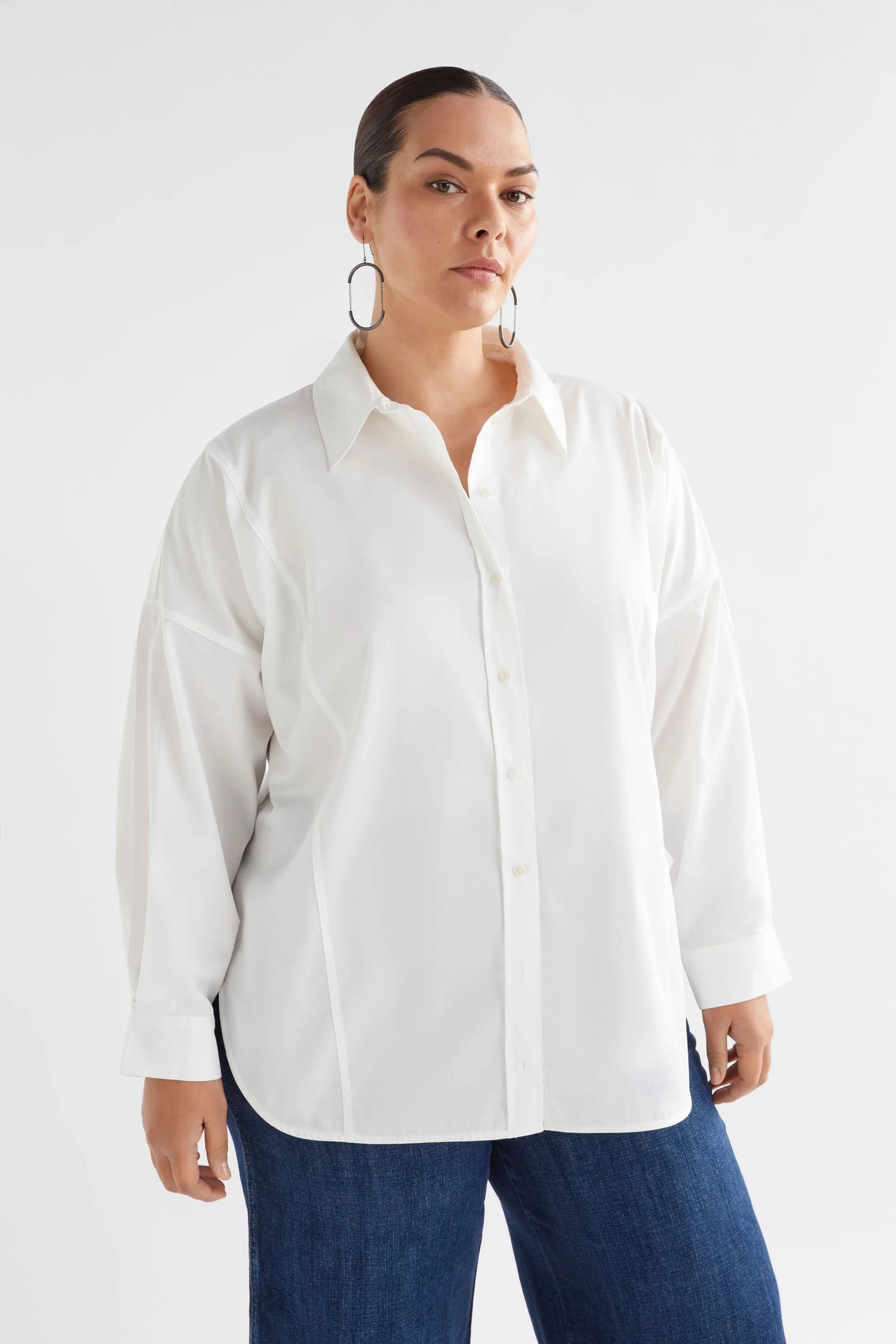 Plus size woman wearing tiga shirt in white and dark denim pants