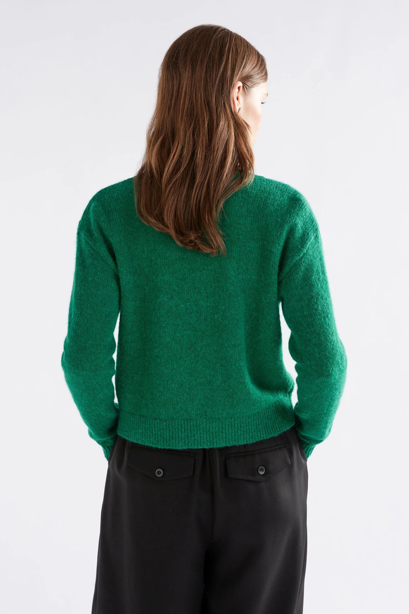 Woman facing the back wearing Daaru Cardigan in Milan Green and black bottoms