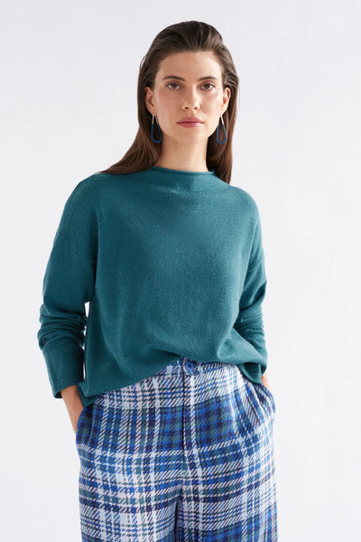 Woman wearing Pirata Sweater in Sea Moss and Blue plaid bottoms