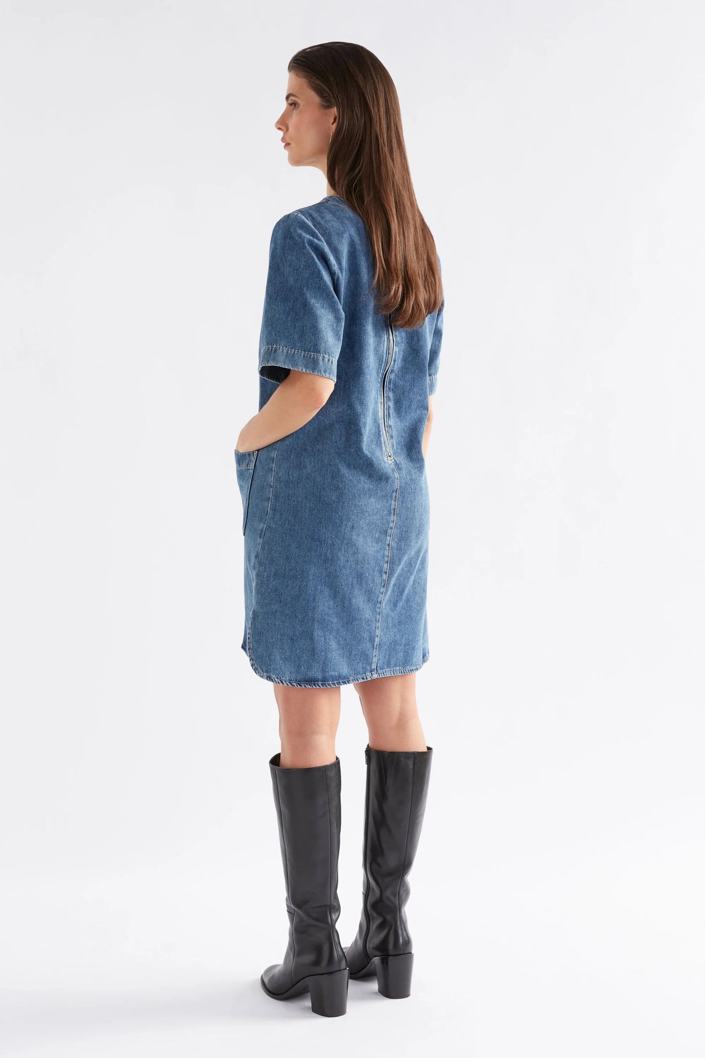 Woman facing the back wearing Rittra Dress in Chambray blue and boots