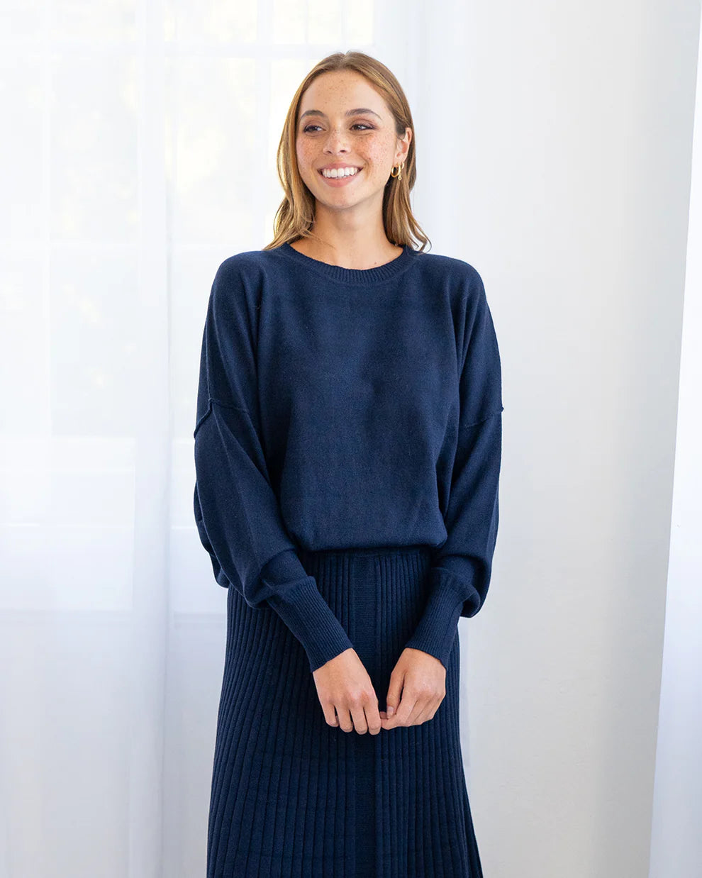 Woman wearing Lucy Knit in Navy and Pleated Skirt in Navy