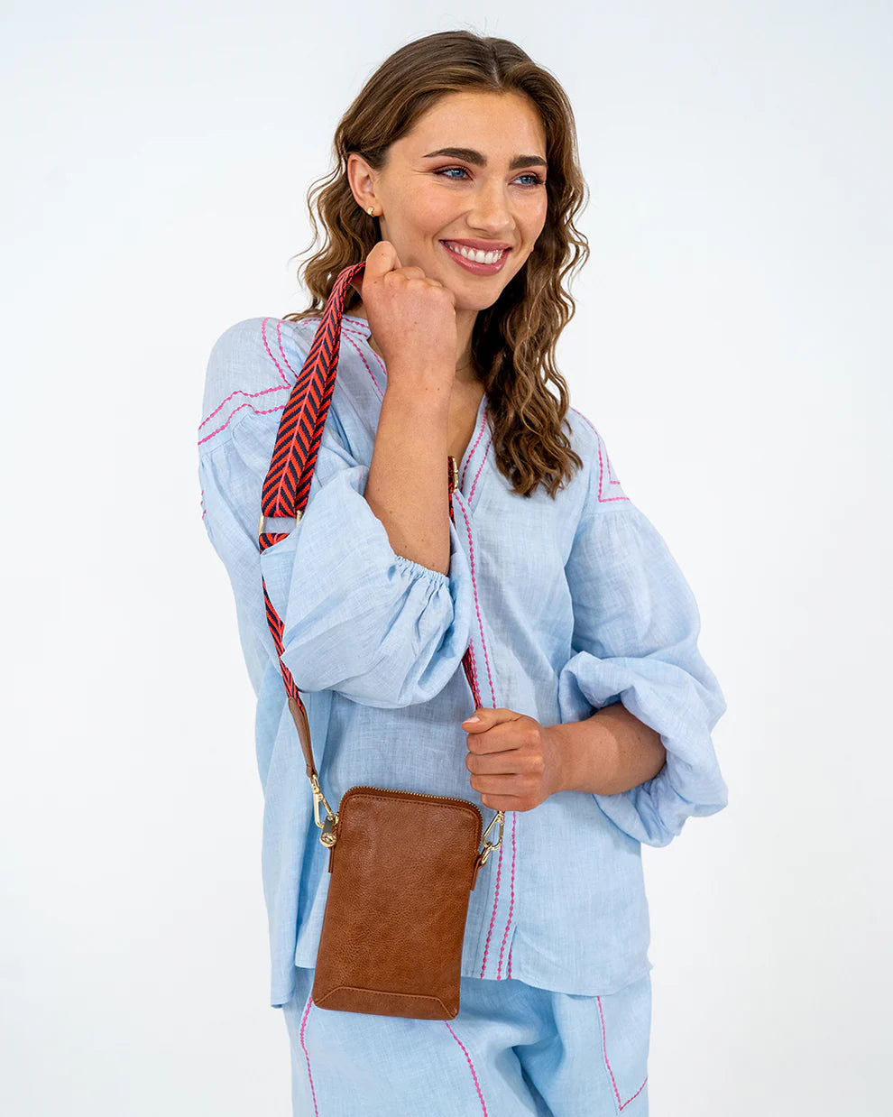 Woman holding Elm and King Sullivan Phone Bag in Tan Pebble