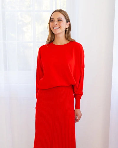 Woman wearing Lucy Knit in Poppy and Pleated Skirt in Poppy colour