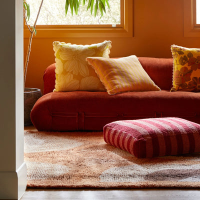 living room sofa with yellow floral cushion and Boucle Stripe Burgundy Pouffe