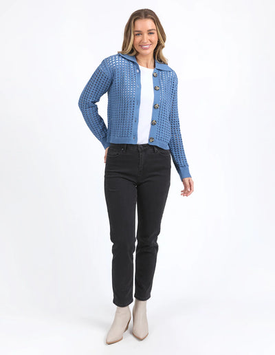 Full image of woman wearing Clover Knit Cardi in Coronet Blue, white top and denim skirt