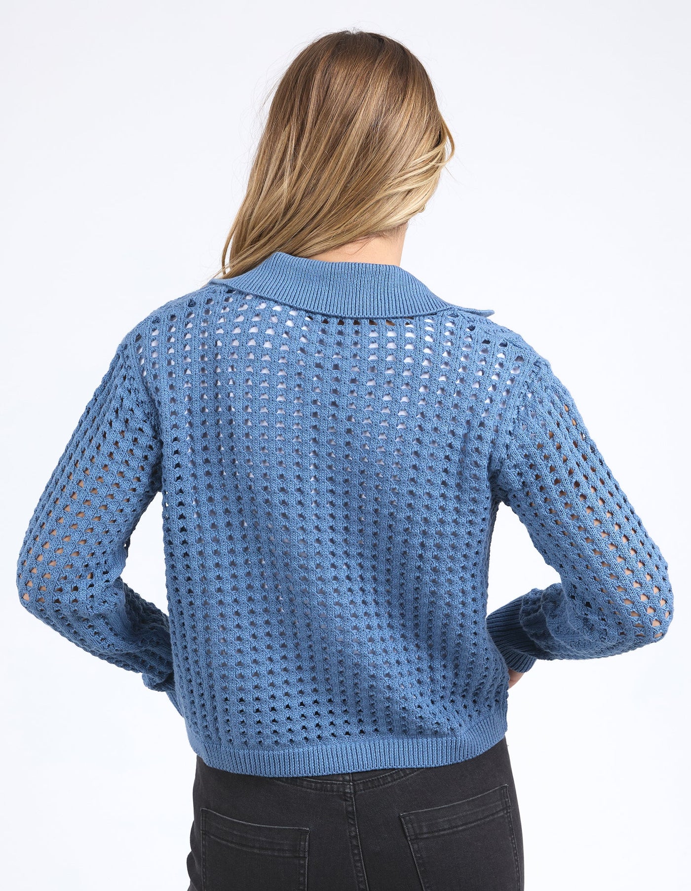 woman facing the back wearing Clover Knit Cardi in Coronet Blue, white top and denim skirt