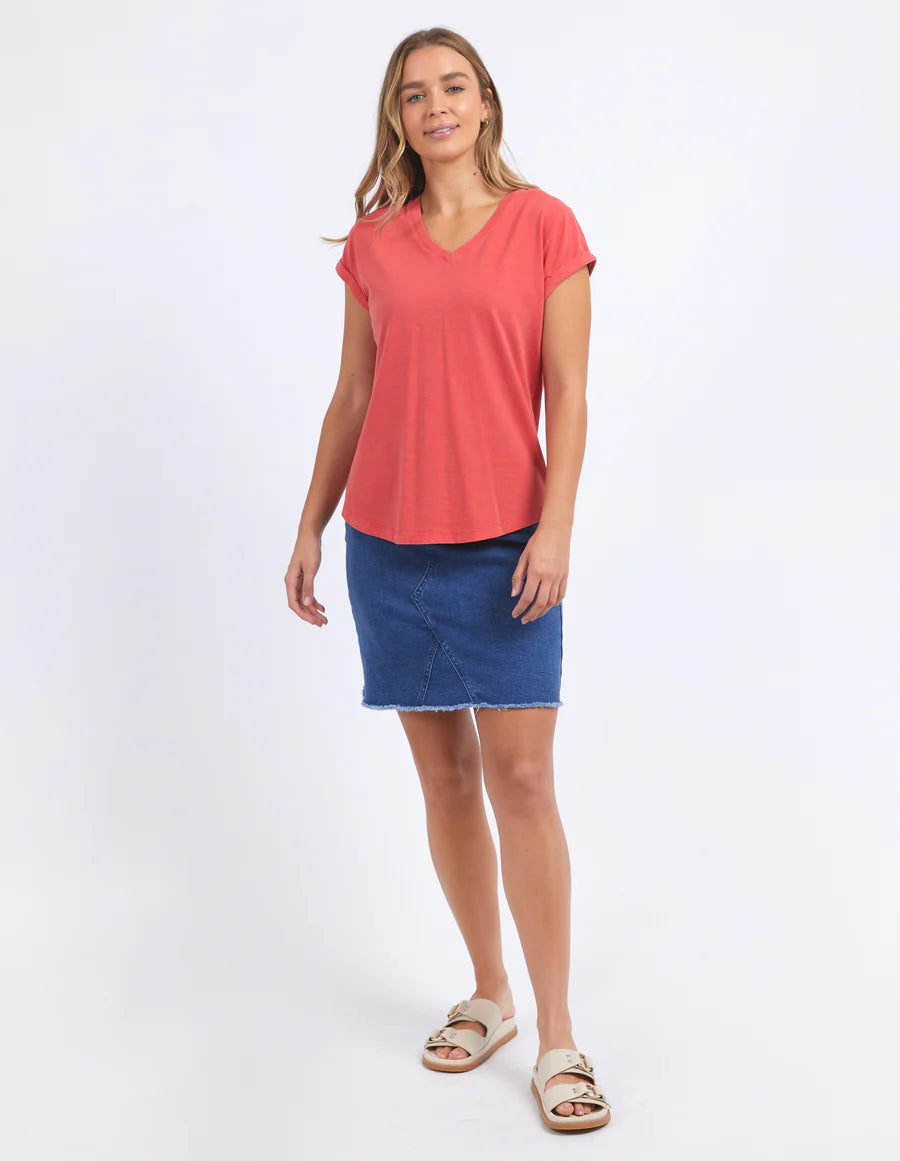 Woman wearing  foxwood manly vee tee in cayenne colour and blue denim skirt and slip on