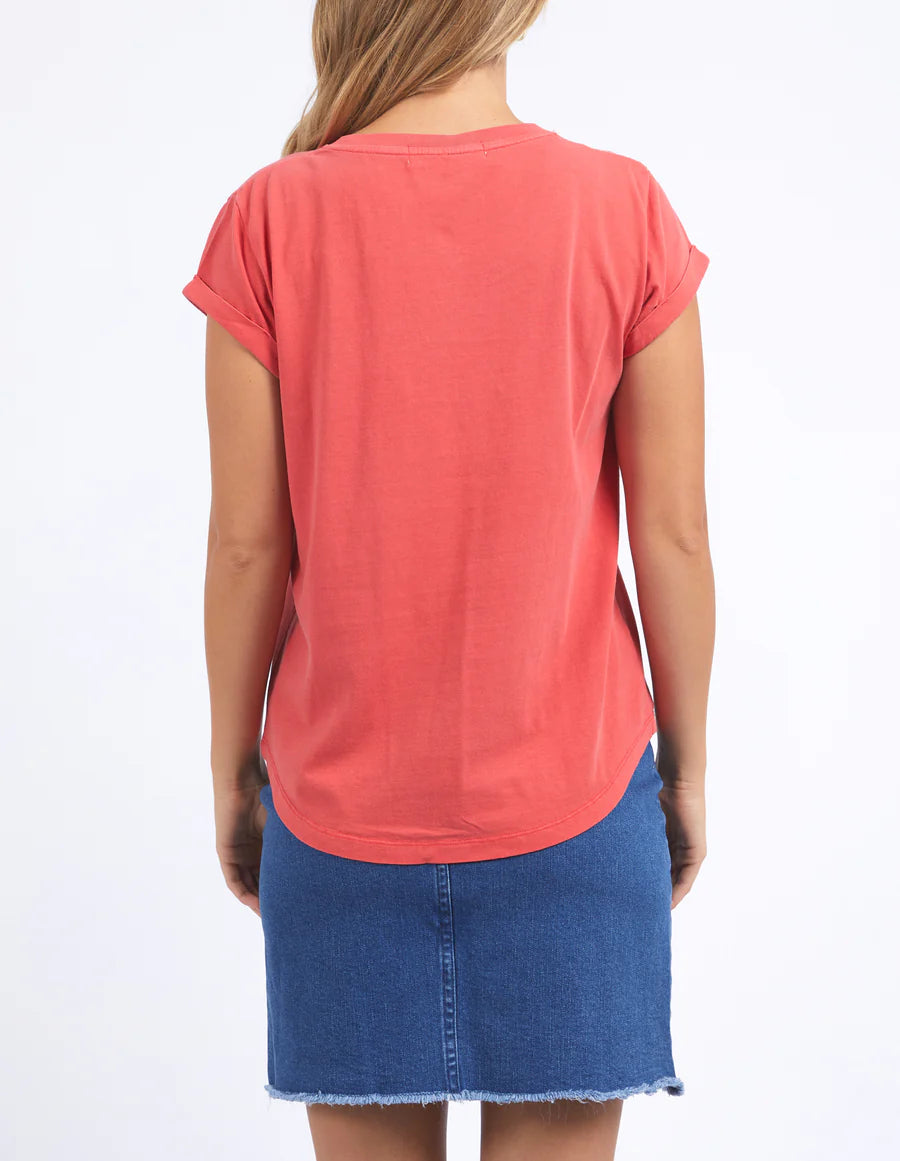 Woman standing facing the back wearing  foxwood manly vee tee in cayenne colour and blue denim skirt