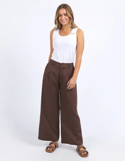 woman wearing white sleeveless top and foxwood pierra pants in chocolate colour