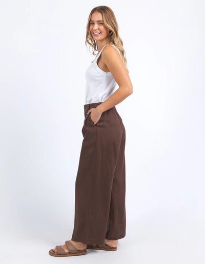 woman wearing white sleeveless top and foxwood pierra pants in chocolate colour