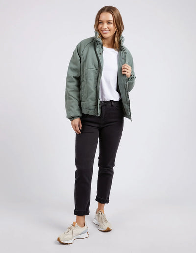 Full image of Woman wearing white top with Rosalee Jacket in Washed Green, and black pants