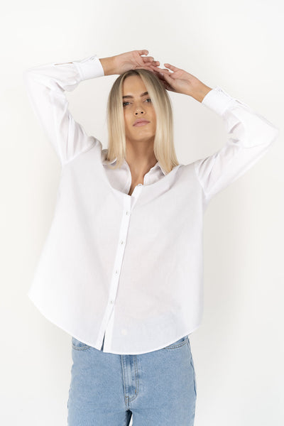 Woman wearing white long sleeve Stephanie shirt and denim pants