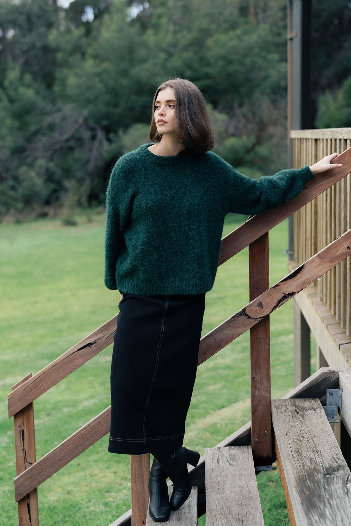 Woman wearing long black denim skirt and Jumper in green