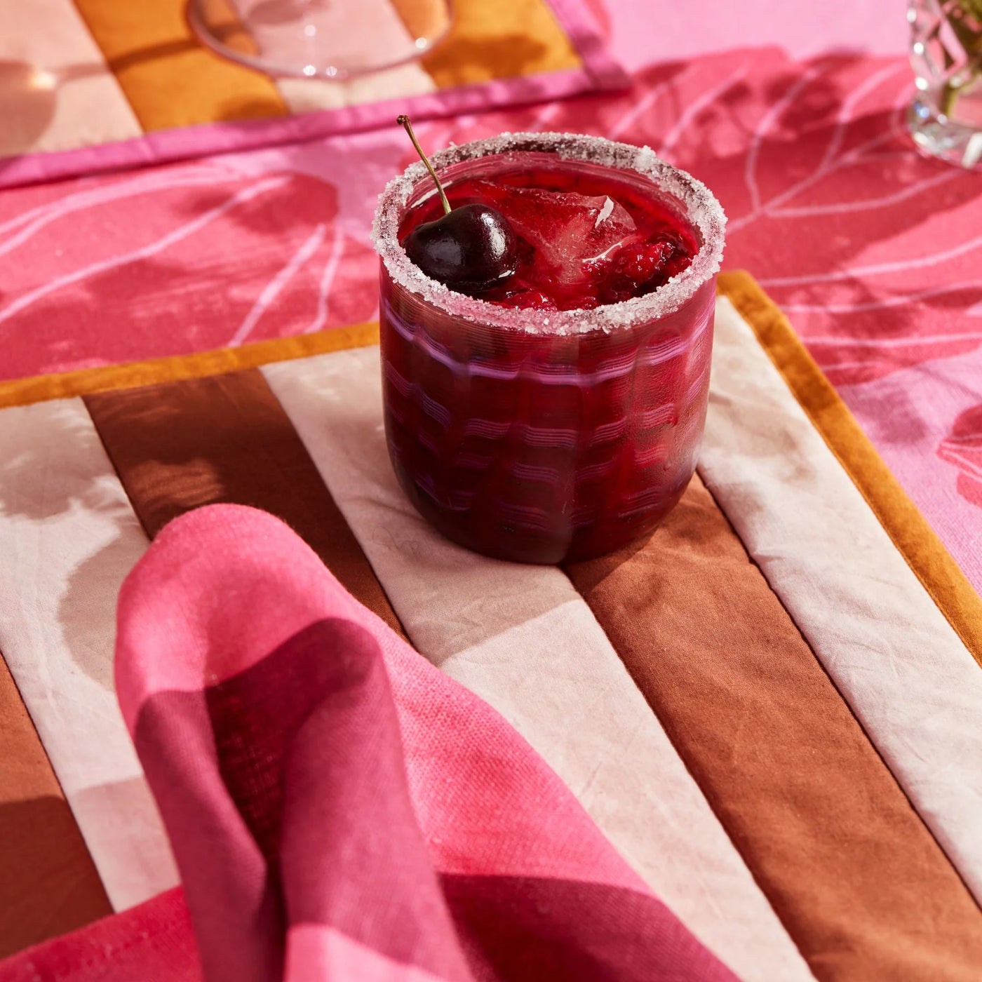 juice filled glass placed on table with flower print table cloth with bonnie and neil big stripe cerise napkins set of four