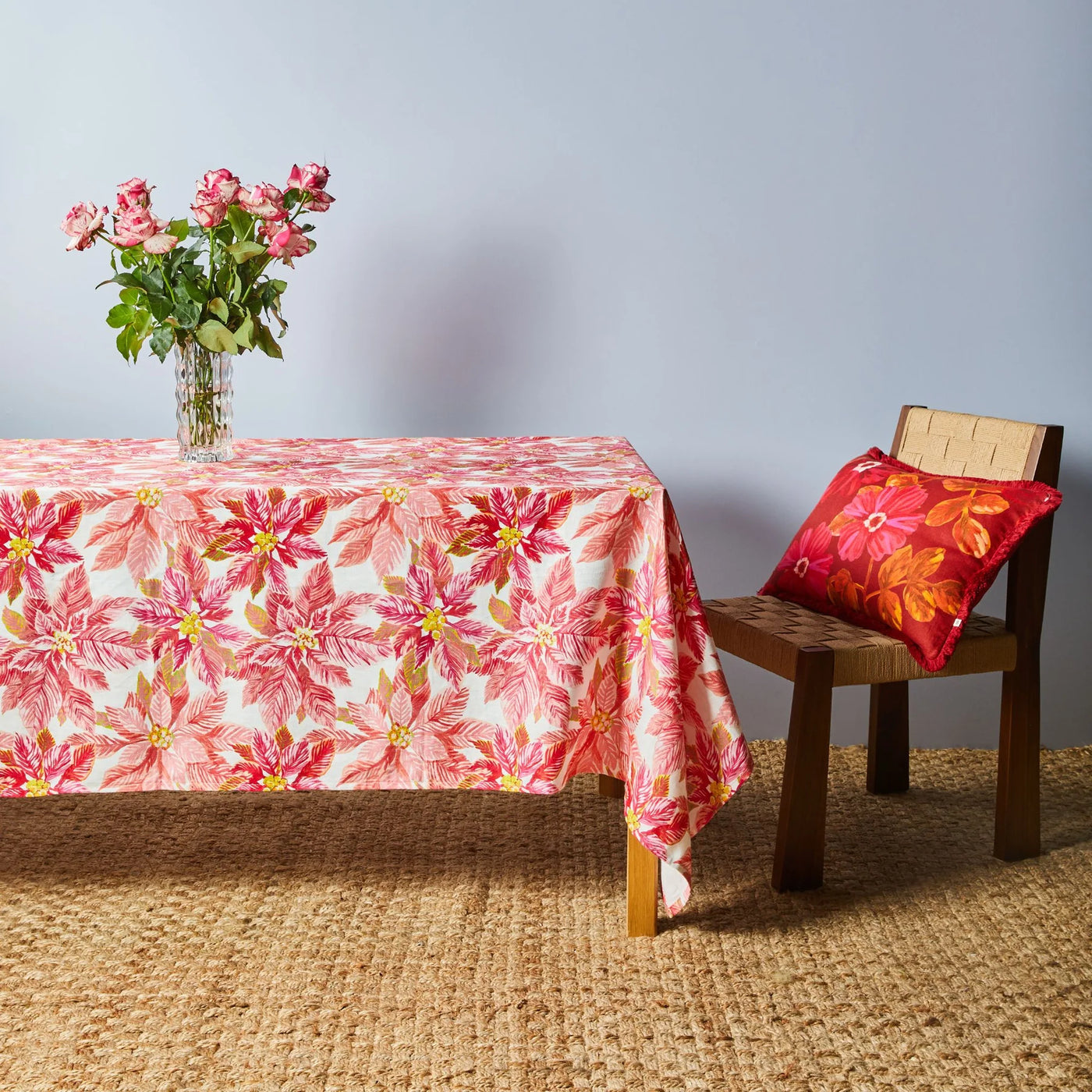 vase with roses placed on table with bonnie and neil poinsettia red tablecloth