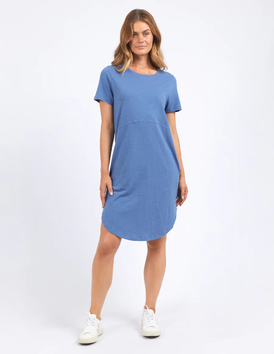 Woman standing wearing Foxwood bay dress in blue horizon and with white shoes