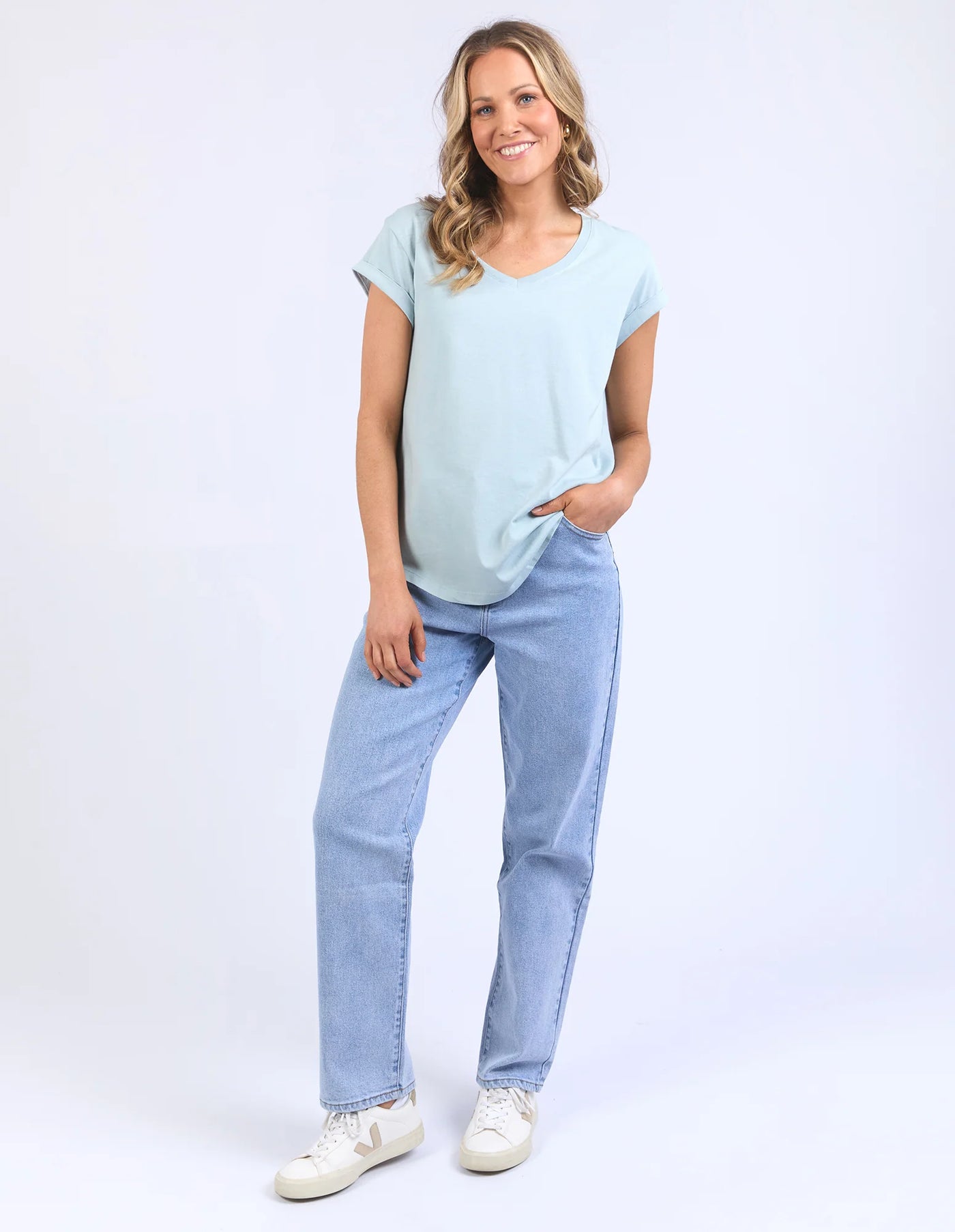 woman wearing foxwood manly vee tee blue bell, denim pants, and white shoes