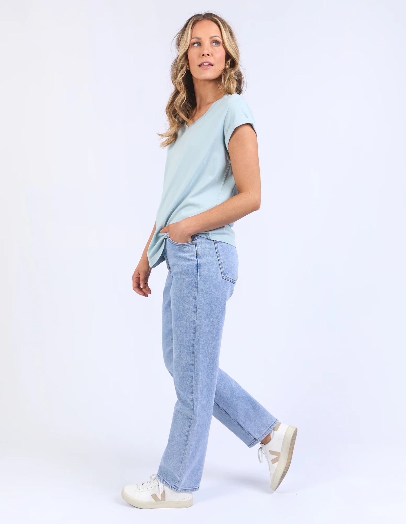 woman wearing foxwood manly vee tee blue bell, denim pants, and white shoes