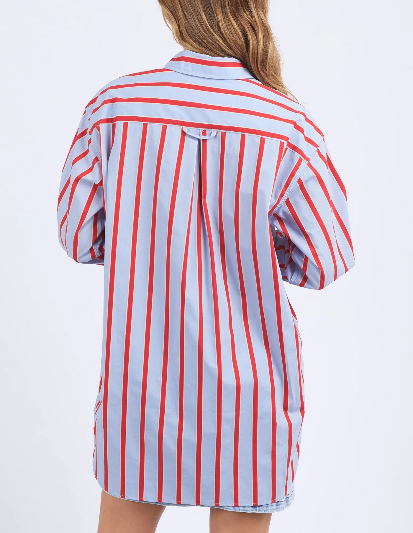 woman facing the back wearing foxwood strike shirt in blue and red stripe and denim skirt