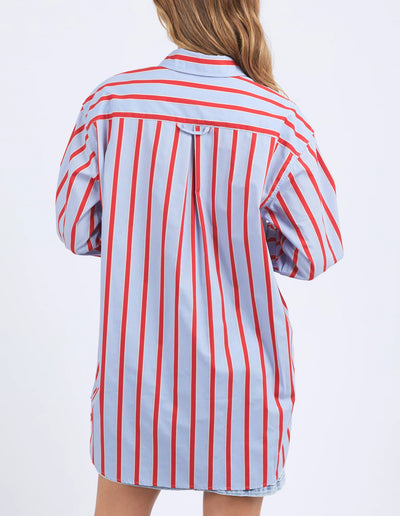 woman facing the back wearing foxwood strike shirt in blue and red stripe and denim skirt