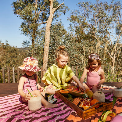 three kids playing, one kid wearing sage and clare jarita hooded towel in palm colour