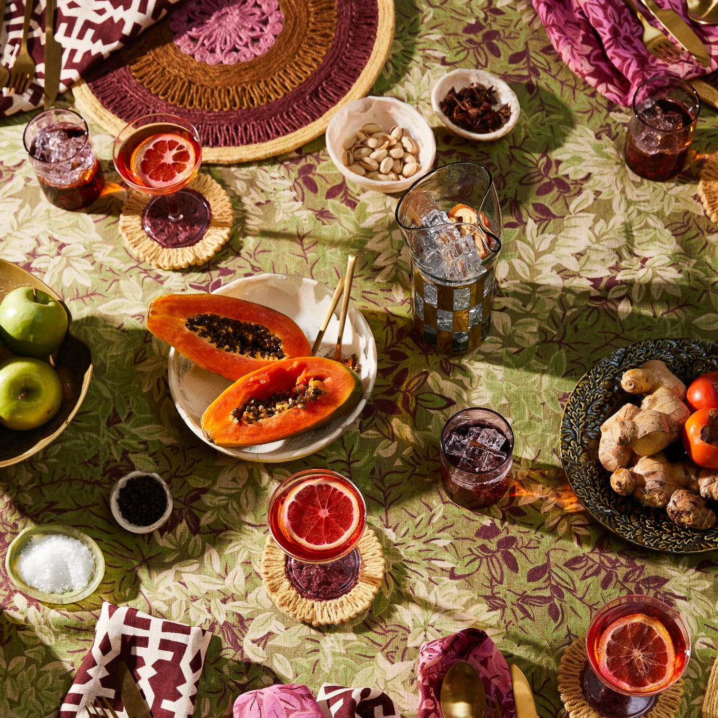 A table setting with colorful textiles, sage and clare toni bowl vanilla, and fresh fruit.